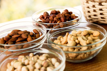 Assortment of mixed nuts and wicker basket on wood table background