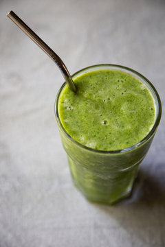 Green juice in glass with metal straw