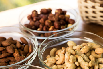 Assortment of mixed nuts and wicker basket on wood table background