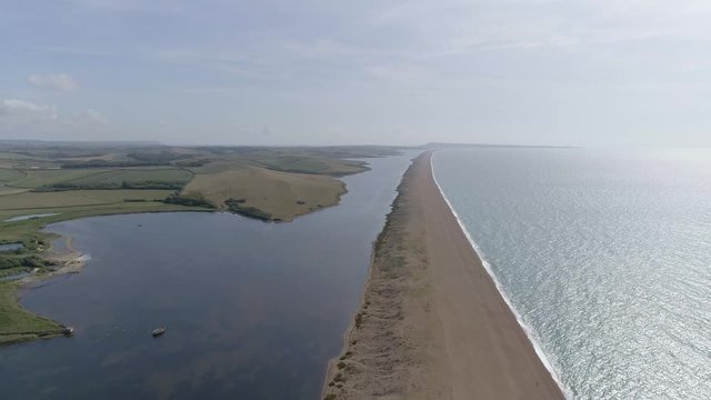 Aerial tracking along the grand barrier that is Chesil Beach on the Dorset coast. Shot looking east toward Weymouth and Portland Bill.