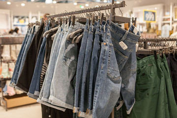 Jeans shorts on the store shelf. Fashionable clothes on the shelves in the store. Jeans hanging on the vests in the fashion store. Showcase, sale, shopping