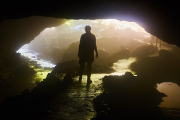 Fototapeta premium Silhouette of Figure in Dark Foggy Cave with River