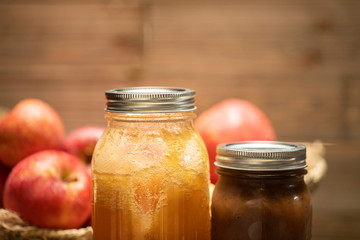 jars of freshly made apple butter and honey with a basket of apples in the background