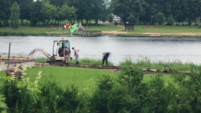 A mini excavator burying the pit on the bank of the river. Time lapse