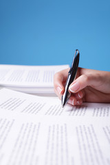 Unrecognizable person reviewing a text (focus on pen and shallow depth of field)