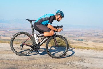 Fototapeta premium Cyclist riding the bike in the road descending the hill