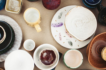 Ceramic tableware and cutlery on wooden background. Сoncept pottery of different colors. Top view, flatlay, сopy space for text.