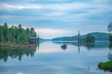 Fototapeta na wymiar Calm Palmerston Lake with a fisherman in a boat