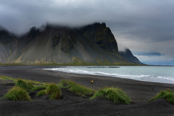 Colorful panorama of the Stokksnes headland on southeastern Icelandic coast with Vestrahorn (Batman Mountain). Iceland, Europe. Lonely man walking along the baech