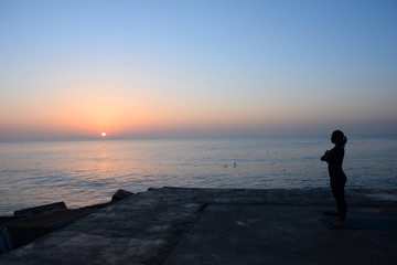 Fototapeta premium Practicando yoga frente al mar al amanecer