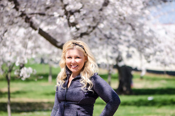 Attractive blonde woman wearing athleisure clothing poses in front of Cherry Blossom trees in Washington DC during the Cherry Blossom Festival