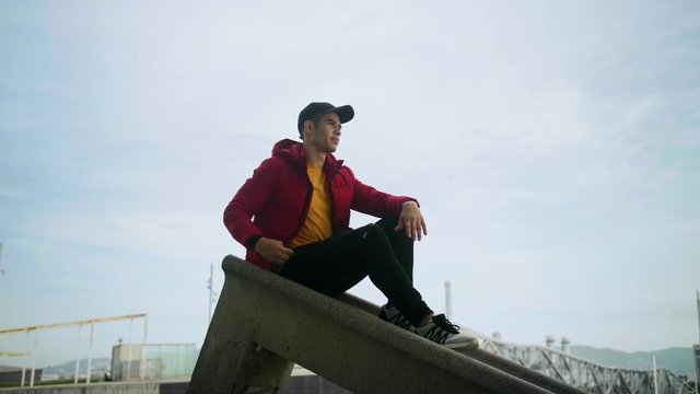 Young Attractive Trendy young Man interacting callling and messaging with a cell phone on an urban city background in slow motion