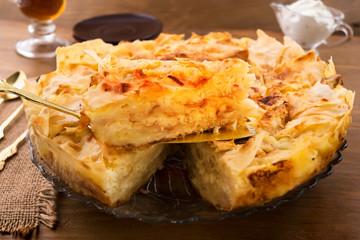Sweet dessert of dough with cottage cheese filling, cut a piece of cake on a metal spatula.