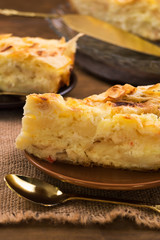 A sliced piece of cake with a layer of cottage cheese, a teaspoon on a linen cloth napkin.