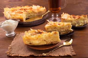 Dough cake with curd layer, cut into portions, wooden background.