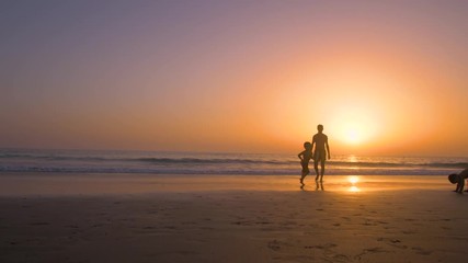 Silhouette of father with two children in the beach at sunset