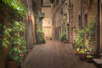 Fototapeta premium Majestatyczna tradycyjnie udekorowana ulica z kolorowymi kwiatami i wiejskimi rustykalnymi domami, Pienza, Toskania, Włochy, Europa