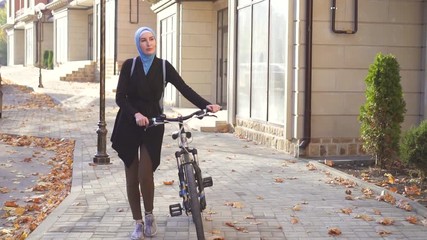 Muslim woman in hijab with a bicycle in the city,slow mo