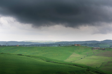 Dramatic view of green fields and meadows at sunset in Tuscany