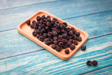 Blackberry in wooden rectangular bowl. delicious black raspberry on cyan blue grunge wooden table, top view