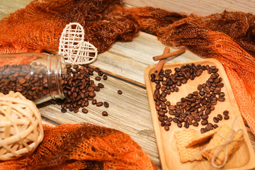 scarf, glass jar, cookies, cinnamon sticks and scattered coffee beans on vintage wooden table. Top...