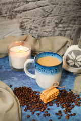 Autumn and winter background with candle, scarf, mug of cocoa, coffee or hot chocolate with scattered coffee beans