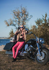 Fototapeta na wymiar Biker blond woman outdoor with her motorcycle. 
