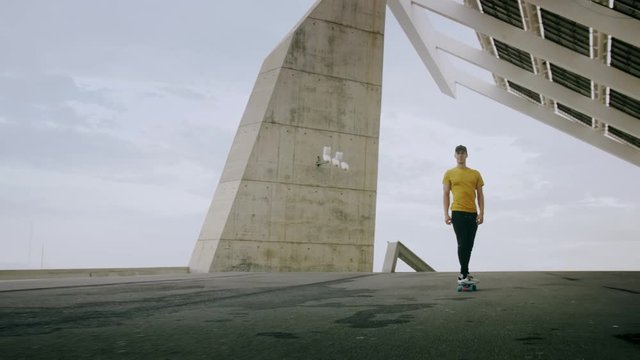 Epic Portrait and close upt of a Young Attractive Trendy Man skateboarding fast under a solar panel on a morning sunny day with an urban city background in slow motion