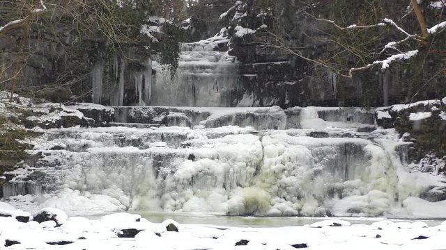 Frozen waterfall with snow falling at Cotter Force in the Yorkshire Dales National Park
