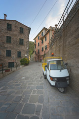 Fototapeta na wymiar Historic buildings of Vernazza, Liguria, Italy, typical street with folk motorbike parked on the sidewalk