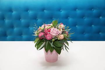 Colorful roses on a white table near a turquoise sofa