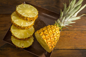 Fototapeta na wymiar Pineapple on wood texture background. Whole and sliced tropical pineapple on wooden cutting board.