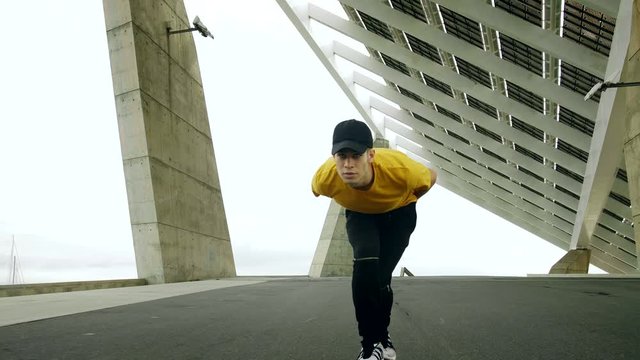 Epic Portrait and close upt of a Young Attractive Trendy Man skateboarding fast under a solar panel on a morning sunny day with an urban city background in slow motion