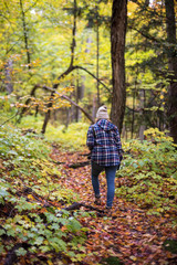 woman hiking in fall leaves on forest trail