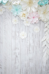 Pastel paper flower; cream, white, pink, green, blue with hand craft art on the white wood plate background.