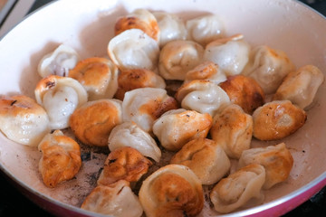 Dumplings frying on a pan on table.