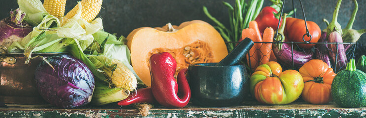 Fall vegetarian food ingredients. Assortment of vegetables for healthy cooking over rustic cupboard, dark wall background, copy space, selective focus, wide composition. Local market organic produce