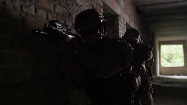 Subdivision of anti-terrorist police during tactical exercises entering the premises. Group of soldiers carrying guns preparing for help hostage in abandoned building during anti terrorism operation.