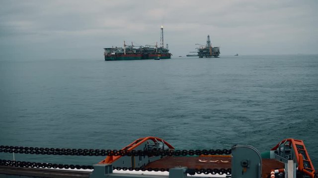 Anchor-handling Tug Supply AHTS vessel during dynamic positioning DP operations near FPSO tanker. Ocean tug job.