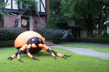 The house is decorated for Halloween:Huge inflatable spider near the entrance to the house and the web. Evening, Houston, Texas, United States