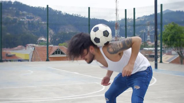 Handsome guy doing soccer tricks on a skate park