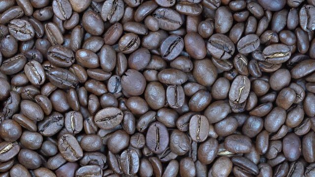Fried coffee beans background, close up, rotation loopable 4k top view. Food  background. Gastronomy concept, organic food. Macro coffee beans