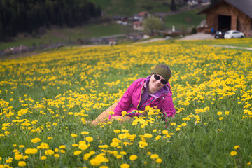 Active healthy woman having rest on beautiful meadow covered with flowers. Portrait of happy smiling young woman resting of mountains clearing during hike holidays