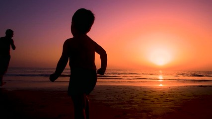 Silhouette of father with two children in the beach at sunset