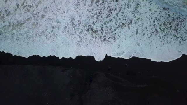 Waves coming up onto the black sand beach near Vik in Iceland from drone
