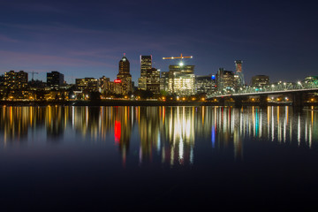 Portland Oregon downtown skyline at night with reflections in Willamette River.