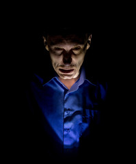 Fototapeta premium Stylish dark portrait of adult caucasian man who seems like maniac or psycho. Isolated on black background. Low-key lighting.