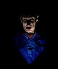 Stylish dark portrait of adult caucasian man who seems like maniac or psycho. Isolated on black background. Low-key lighting.