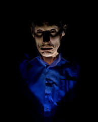 Stylish dark portrait of adult caucasian man who seems like maniac or psycho. Isolated on black background. Low-key lighting.