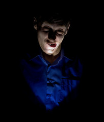 Stylish dark portrait of adult caucasian man who seems like maniac or psycho. Isolated on black background. Low-key lighting.